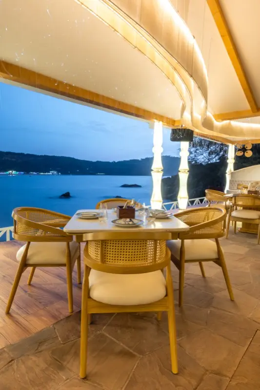 Evening seaside dining with illuminated ceiling and ocean view
