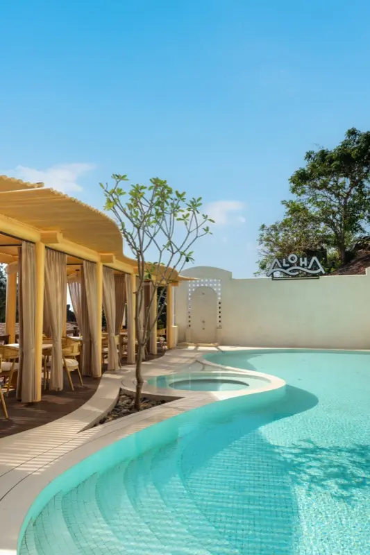 Pool with Aloha sign and sheer cabana curtains in daylight
