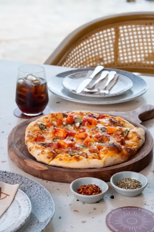 Wood-fired pizza on board with chilli flakes and seasoning