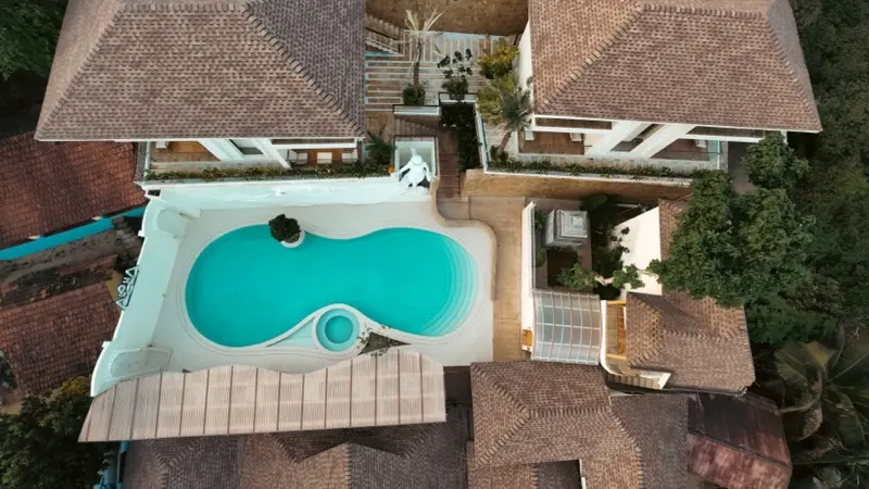 Aerial drone view of Aloha Resort with infinity pool and villa rooftops