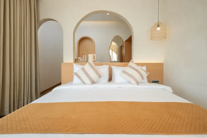 Room 102 bed frontal with arched mirror and pendant light
