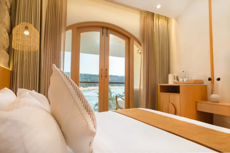 Room 203 bedroom with stone wall, under-bed lighting and sea view