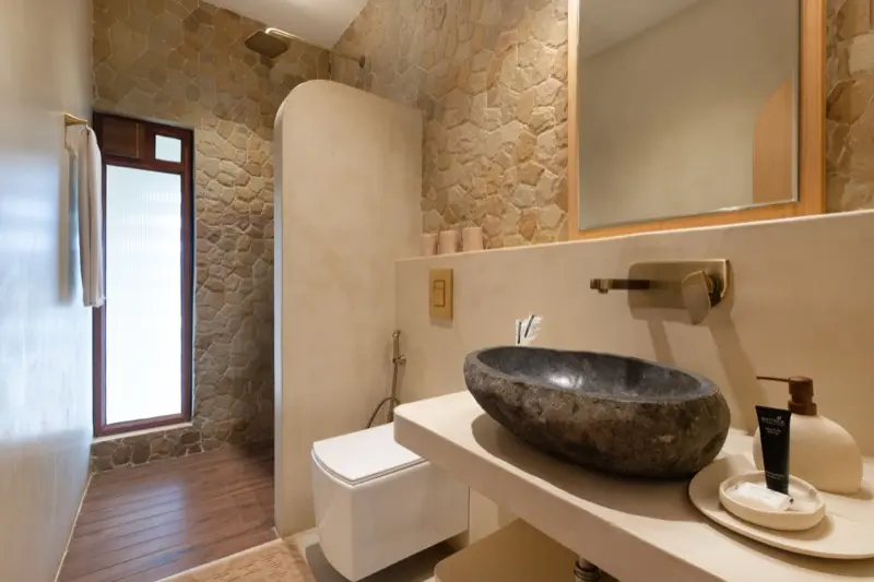 Bathroom with stone vessel sink and natural stone walls